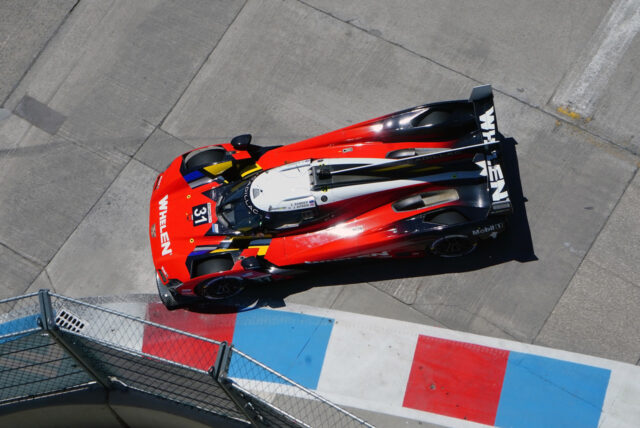 Top-down view of a red endurance race car with number 31 on a racetrack, viewed from above with track barriers nearby