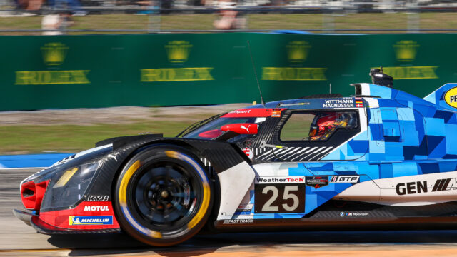 Blue and white race car #25 speeding on a racetrack, sponsor logos visible along the body and a blurred background indicating high speed.